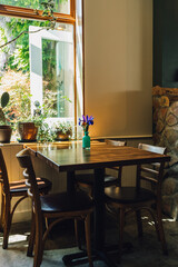 four top wooden table at restaurant with vase of purple flowers
