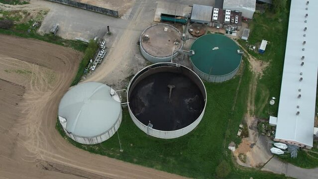 Aerial view of agricultural complex of barns and biogas production domes and storage tanks, bio renewable energy generation from rural landscape
