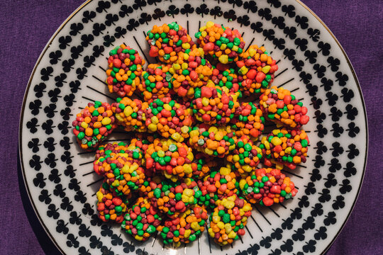 colorful clusters of candy on patterned black and white plate, purple background