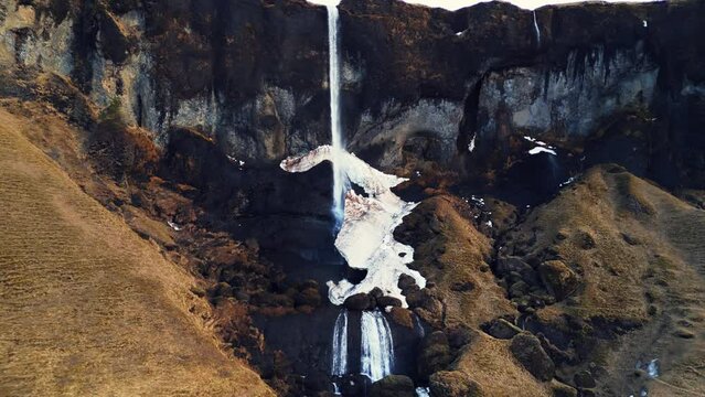 Drone shot of foss a sidu waterfall in iceland falling off cliff creating beautiful panoramic view, scenic route. Fantastic nordic cascade with stream flowing down of icelandic hills. Slow motion.