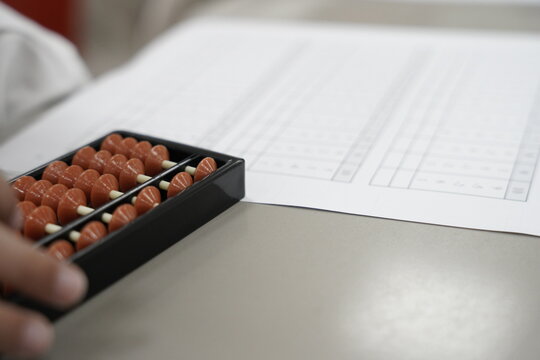 A kid is solving math problems on a paper. a child is doing math using mental arithmetic and writing on a paper.