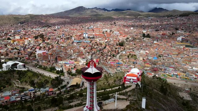Aerial shot drone flies over red tower on hill overlooking silver mining town toward the red clay roof covered buildings