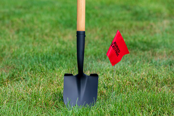 Buried electric line utility warning flag with shovel. Notify utility locate company for...