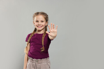 Happy girl giving high five on light grey background, space for text