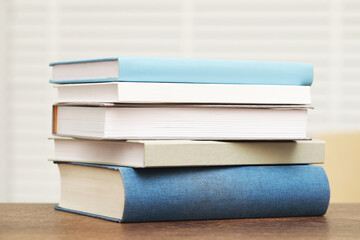 Stack of hardcover books on wooden table indoors
