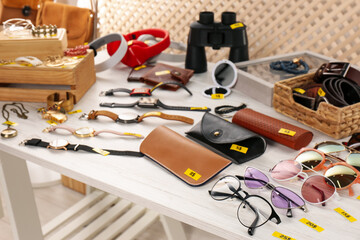 Many different items on white wooden table indoors. Garage sale