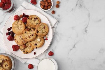 Cookies with freeze dried fruits, milk and nuts on white marble table, flat lay. Space for text