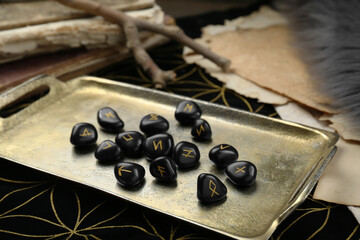 Tray with many black rune stones on divination mat, closeup