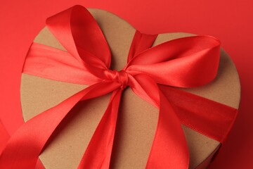 Beautiful heart shaped gift box with bow on red background, closeup