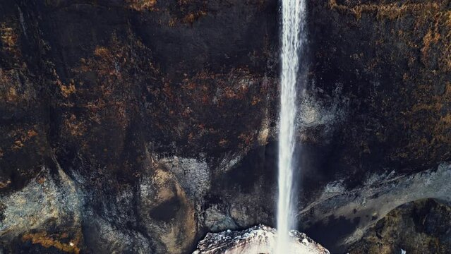 Drone shot of wild foss a sidu cascade, river flow running off frozen cliffs. Icelandic beautiful waterfall in iceland flowing down off mountains, fantastic panoramic landscape. Slow motion.