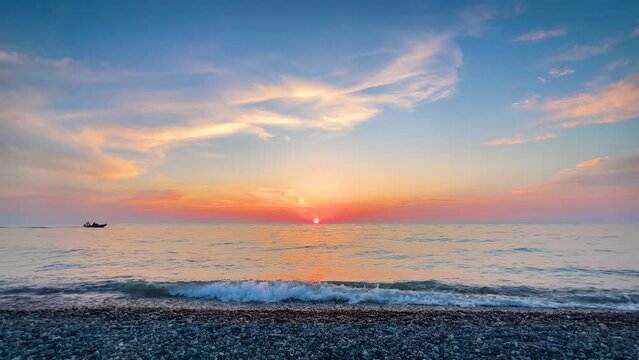 Amazing dramatic sunset over the sea surface in the evening. Many clouds in the evening sky. Waves is crashing on the pebble beach. Seascape, summer and nature concept