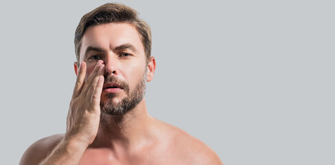 Fototapeta premium Close up beauty portrait of satisfied man after facial cream. Attractive brunet guy touching skin. Men model face with beard and modern haircut. Banner for header, copy space. Poster for web design.