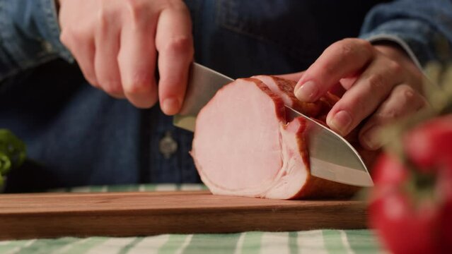 Woman slices ham bacon meat thick pieces on a wooden board, beef or pork jamon. Chef cooking breakfast, smoked bacon in cafe. 