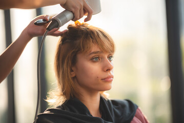 Fototapeta premium Asian Hairdresser giving treatment and barber occupation service, Professional hairstylist combing and using scissors cut woman's hair to young beautiful customer girl in beauty salon