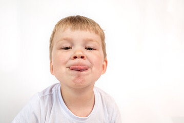 Portrait of a child boy showing his tongue on white background. grimace