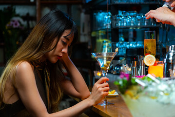 Portrait of Attractive Asian woman relax and enjoy hangout nightlife and drinking fancy cocktail at luxury restaurant bar at night. Beautiful woman celebrating holiday party at nightclub in the city.