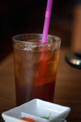 Glass of iced lemon tea with pink straw