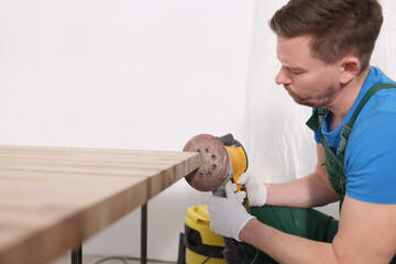 Concentrated worker polishes board edge with grinding tool