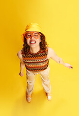 Top view portrait of funny grimacing young girl with curly hair, smiling, posing in panama and...