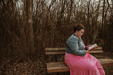 Fototapeta premium woman sits on bench reading a book