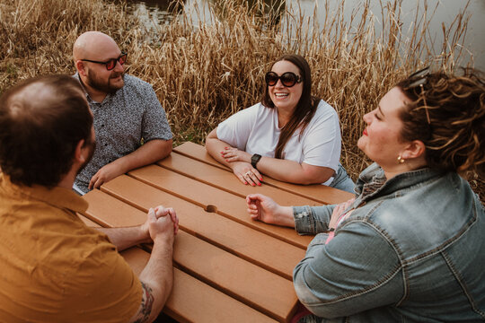 4 friends sit around table laughing