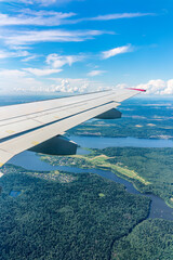Obraz premium View of airplane wing, blue skies and green land during landing. Airplane window view.