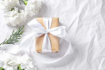 Fototapeta na wymiar Gift box with white flower on crumpled texture background