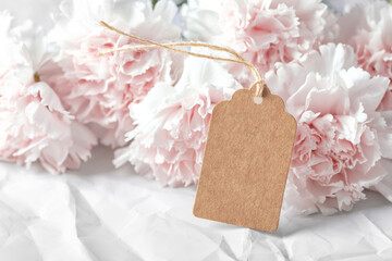 Brown paper tag, closeup with pink flower on crumpled texture