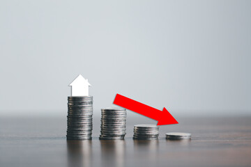 Real estate market, graph, arrow down. Mini house and a stack of coins.The concept of inflation,...