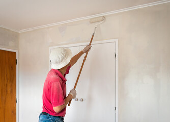 Man painting internal walls with a roller. Home renovation project. Auckland.