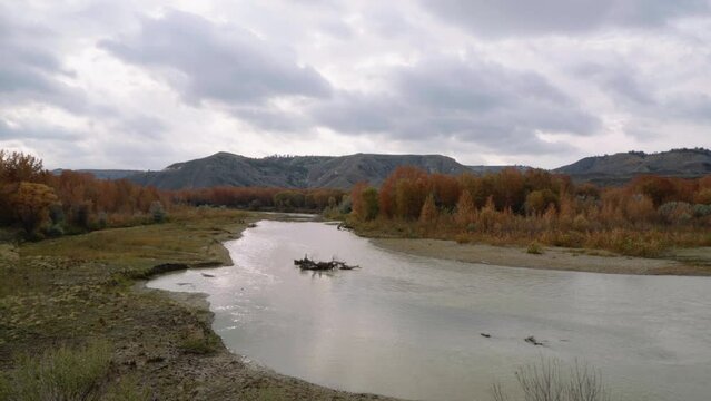 Pan along Judith river bend with orange trees in autumn