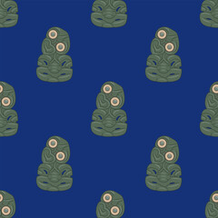 Seamless ethnic pattern with Hei-tiki pendant of the Māori of New Zealand. Green stone carvings with inlaid eyes. Totem figurines. On blue background.