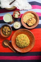 Achari Chicken Khichuri Combo with egg plant and omelet, borhani, salad and Chui Pitha served in dish isolated on mat top view of indian and bangladeshi food