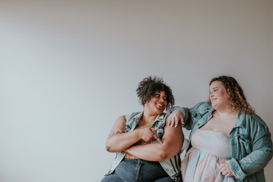 portrait of 2 plus size friends looking at each other