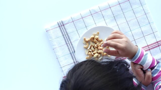 top view of child hand pick peanuts in a bowl on table 