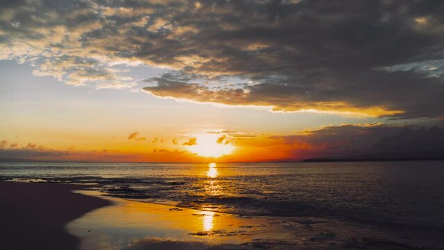 Amazing summer sunset with orange sun on a paradise island in the Atlantic Ocean. Great summer sunset. Waves crash on the shore. Sandy beach goes into the sea against the background of the setting sun