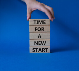 Time for a new start symbol. Wooden blocks with words Time for a new start. Beautiful blue background. Businessman hand. Business and Time for a new start concept. Copy space.