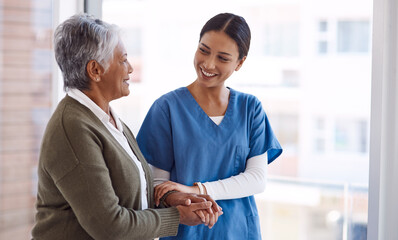 Support, caregiver with senior woman and holding hands for care indoors. Retirement, consulting and professional female nurse with elderly person smiling together for healthcare at nursing home - Powered by Adobe