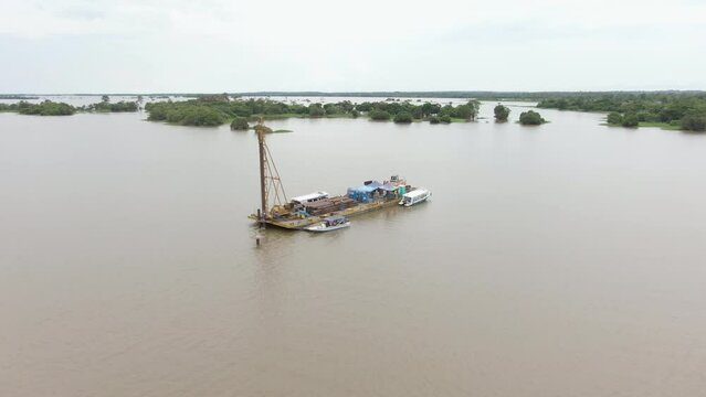 Drone shot around a floating vessel, draging eletric lines over the Amazon river