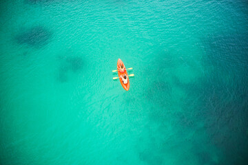 Top view, boat and people in blue ocean together for kayak adventure, travel or journey at sea on mockup. Couple trailing or rowing on big calm, peaceful or serene beach water in nature for kayaking