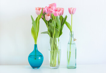 Pink tulips bouquet in glass vase on white background copy space