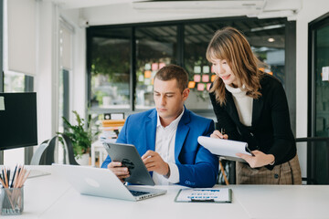 Female discussing new project with male colleague. Mature woman talking with young man in office...