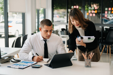 Businessman leading team meeting and using tablet and laptop computer with financial in office