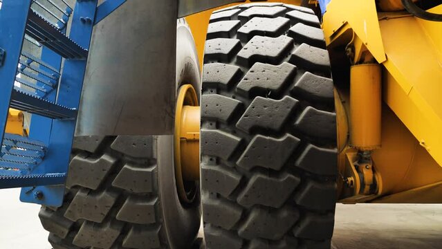 Close-up of the tyre tread on the world's largest mining truck. Large car wheels and suspension components. Tyres of the quarry truck. Bottom-up panorama