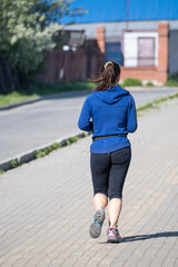 A woman runs along the alley of the park on a spring day