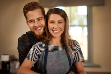 Love, portrait of couple smiling and hugging from the back in a kitchen of their home. Married or relationship, caring or happy and cheerful or excited man cooking with woman in apron in their house - Powered by Adobe