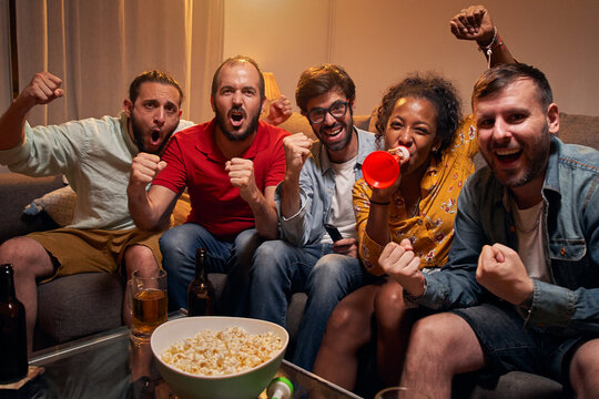 Fans Of A Soccer Team Follow The Game At Home, Celebrating The Winning Goal In The World Cup Match. Enthusiastic People Enjoying The Sporting Success Watching On TV Looking At Camera POV