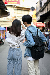 A tourist couple enjoys taking photos and sightseeing the old town market together.