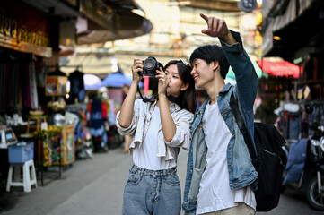 Young Asian tourist couple enjoys taking photos while sightseeing the old town city