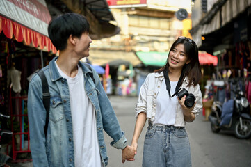A tourist couple holding hands while sightseeing the Chiang Mai old town market together.